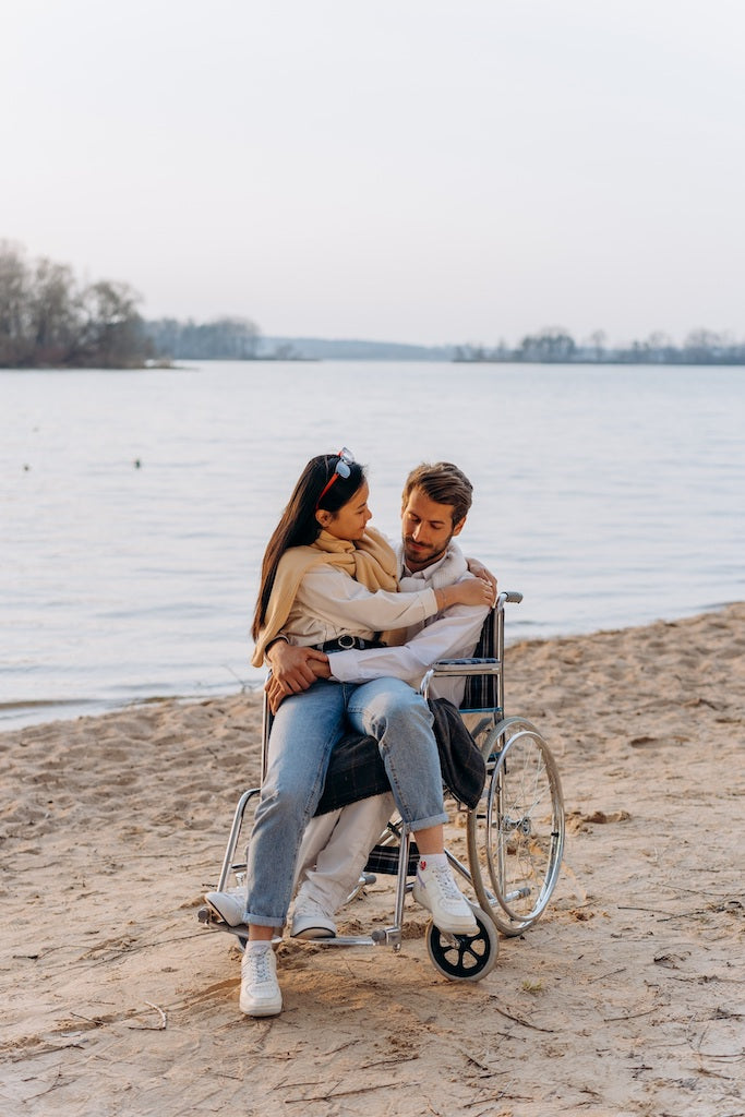 Diverse heterosexual couple with male in wheelchair sharing an intimate embrace on a beach