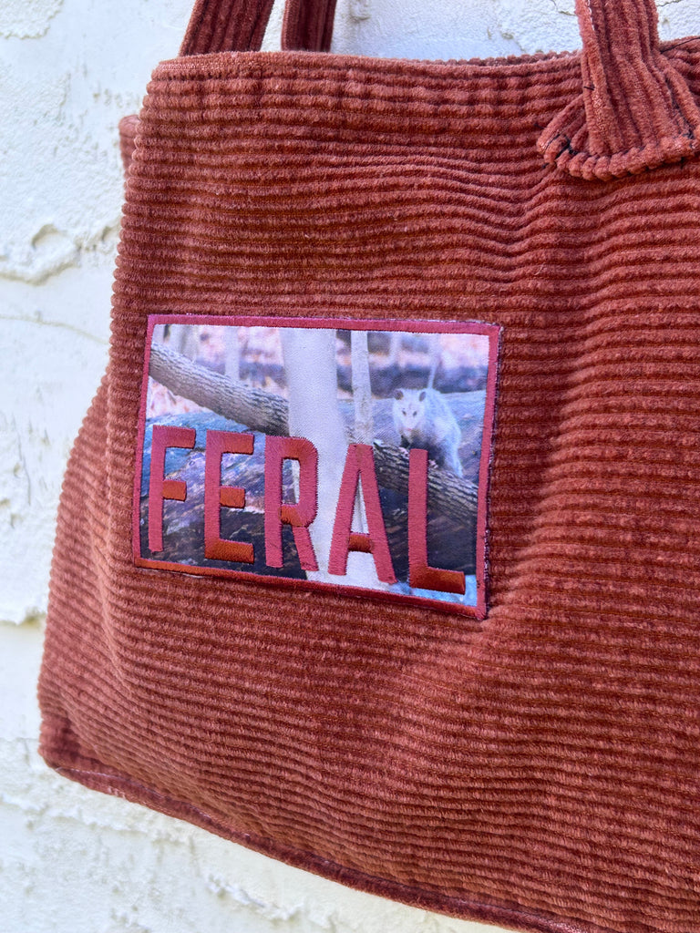 reworked/repurposed / upcycled Brown textured bag with a 'FERAL' patch on a light background