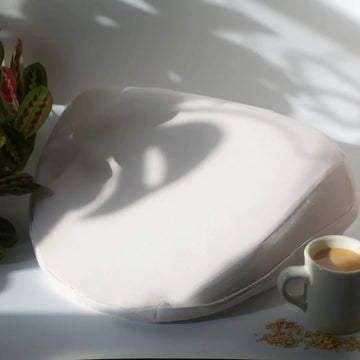 Oat coloured pillo wedge shaped pillow by Dame displayed on beige background. Pillo is a sexual wellness pillow designed to make positions more comfortable and accessible.