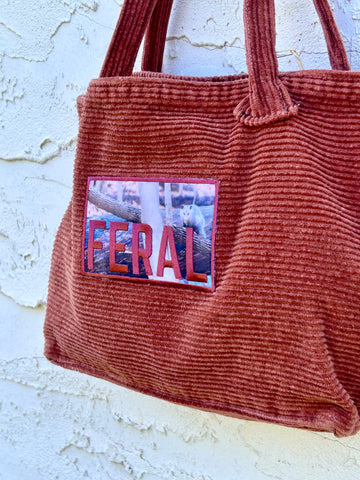 Brown corduroy bag with a 'FERAL' patch on a light background
