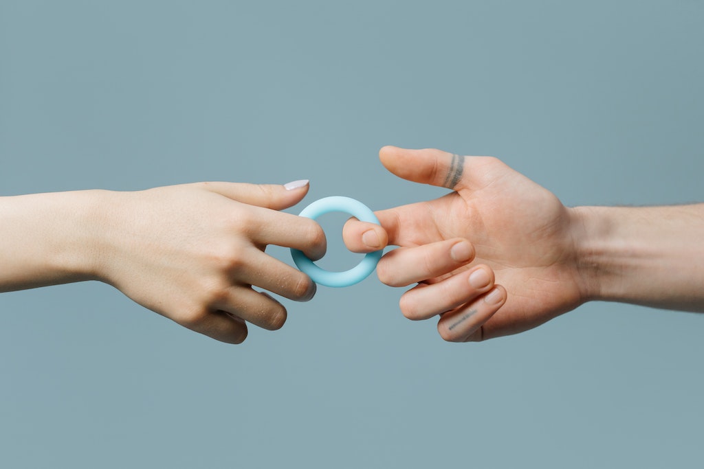 Photo of gender neutral hands with pointer fingers each pulling on a light blue silicone cock ring. 