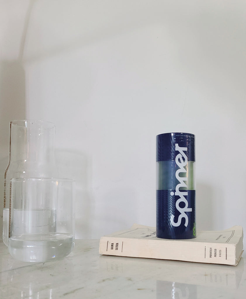 Tenga Spinner in bedroom scene placed on top of book in front of white background. 