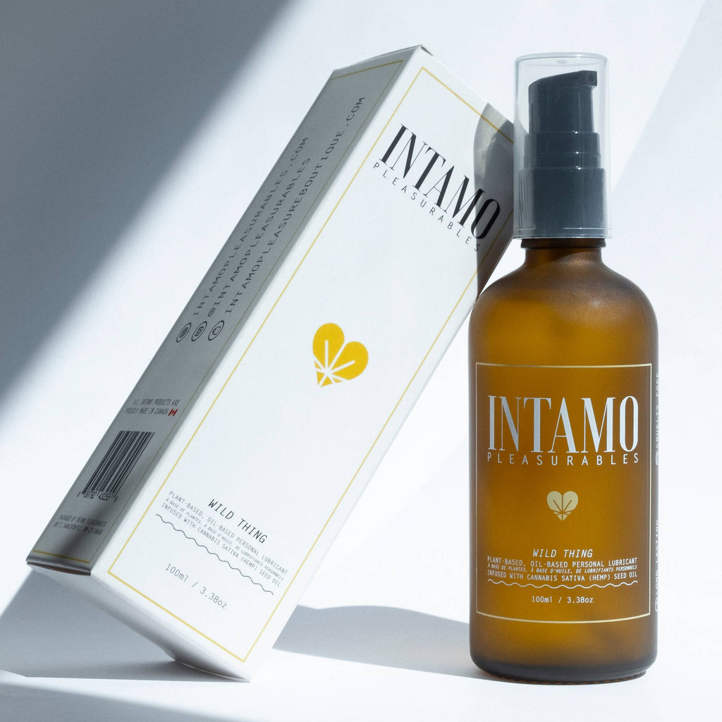 glass brown bottle of intamo wild thing personal lubricant by Intamo. Product is displayed with white box leaning on bottle to the left. Both Lubes are centered in the middle of solid white background.