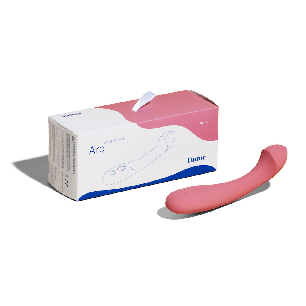 Berry coloured Dame personal massager Arc displayed on solid white background beside product box.
