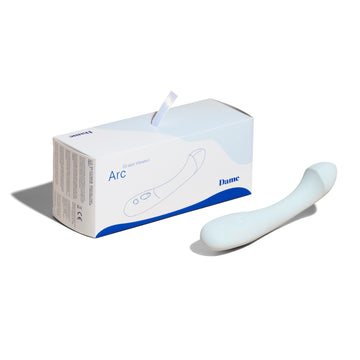 Light blue Dame personal massager Arc displayed on solid white background beside product box. 