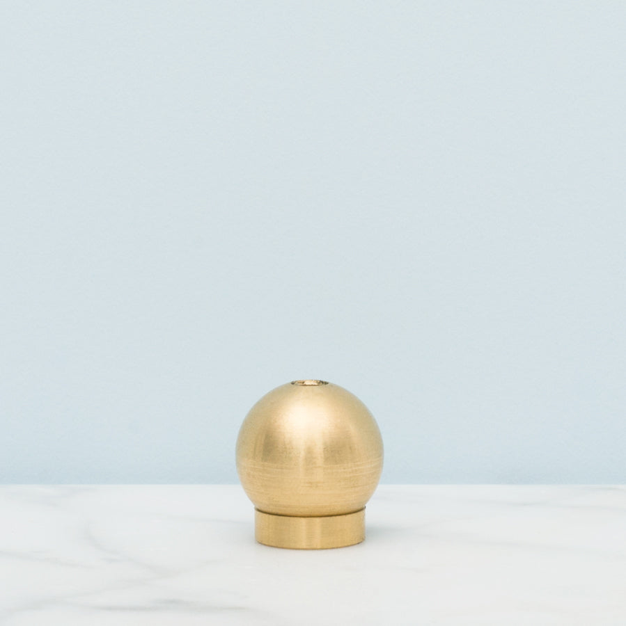Round brass incense holder by province apothecary displayed on light blue background.
