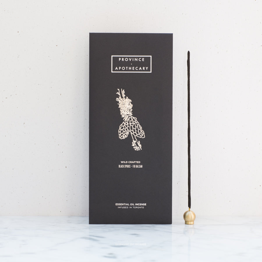 Black foil decorated package of Provice apothecary incense displayed standing against white background.  Province apothecary lunar incense holder displayed beside package with single standing incense. 