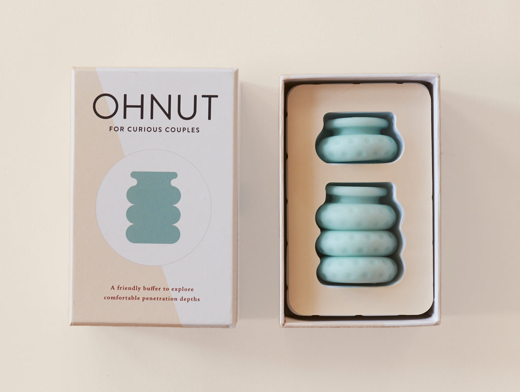 Oh Nut brand silicon intimate wellness buffer in the colour jade, being displayed beside products box laid against peach background