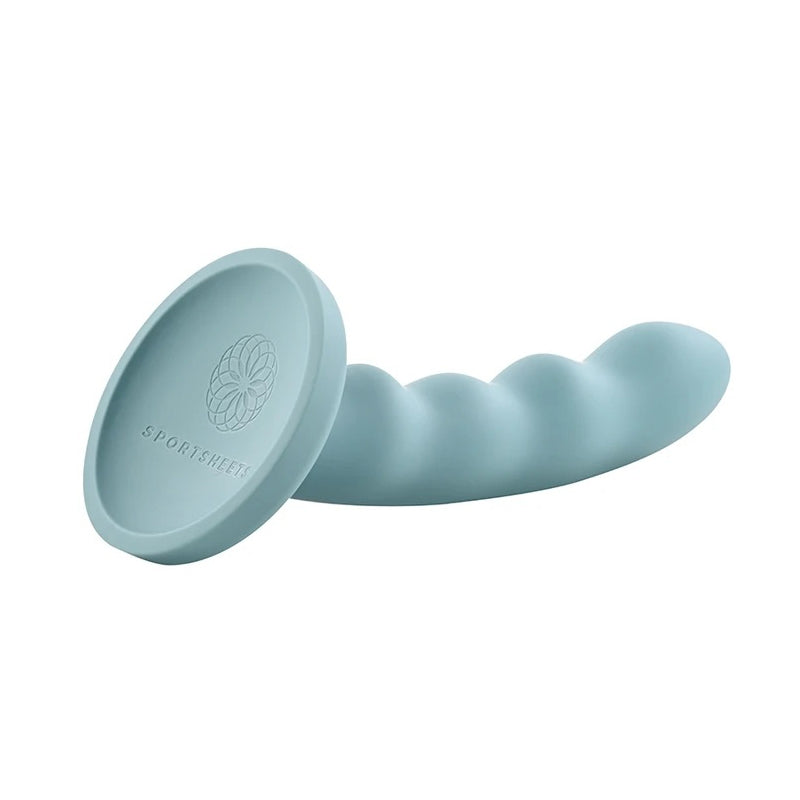 Sage blue silicon dildo sexual wellness and pleasure product being displayed on solid white background. Featuring a suction cup base. 