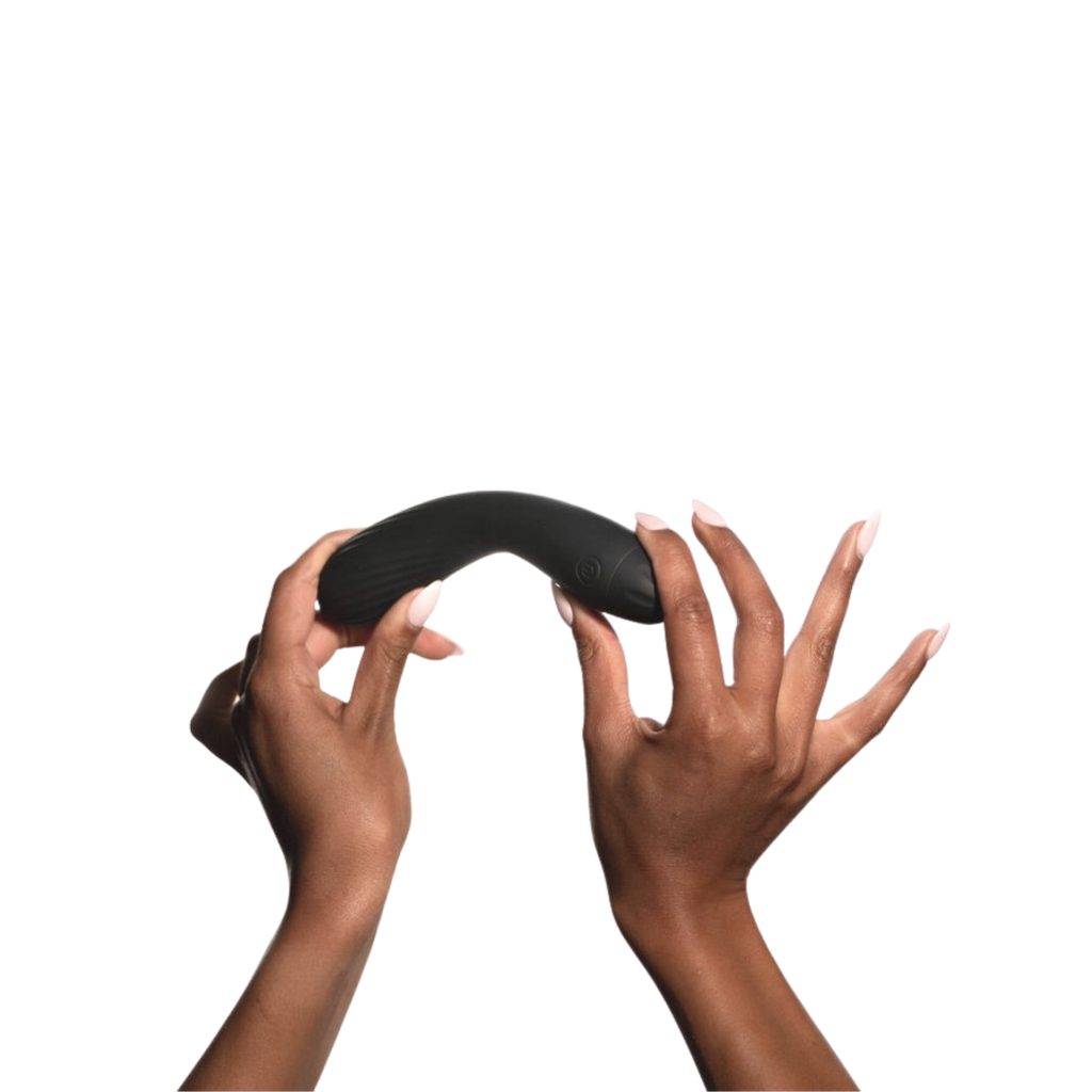 Feminine hands horizontally holding and bending the black silicon Wednesday Co. Flex multipurpose vibrator and dildo against solid white background.