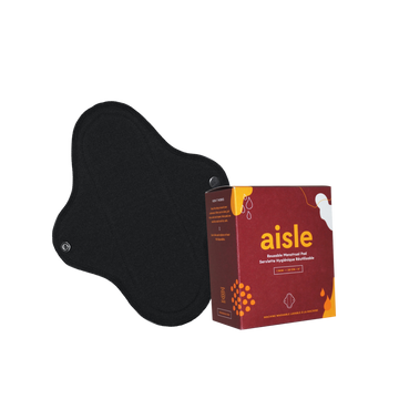 Red decorated box of Aisle mini reusable menstrual pad in front of black cotton pad with snap enclosures in front of white background.