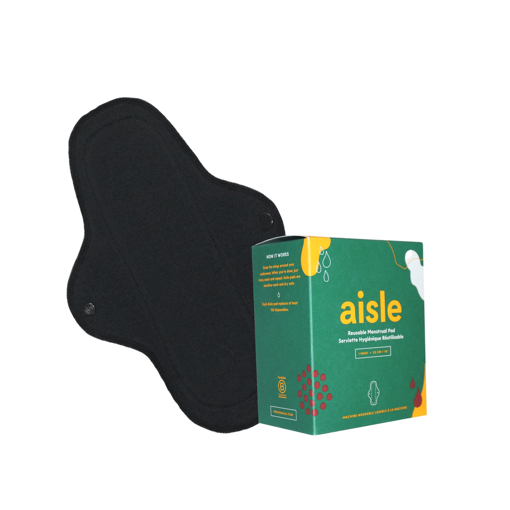 Green decorated box of Aisle maxi reusable menstrual pad in front of black cotton pad with snap enclosures in front of white background.